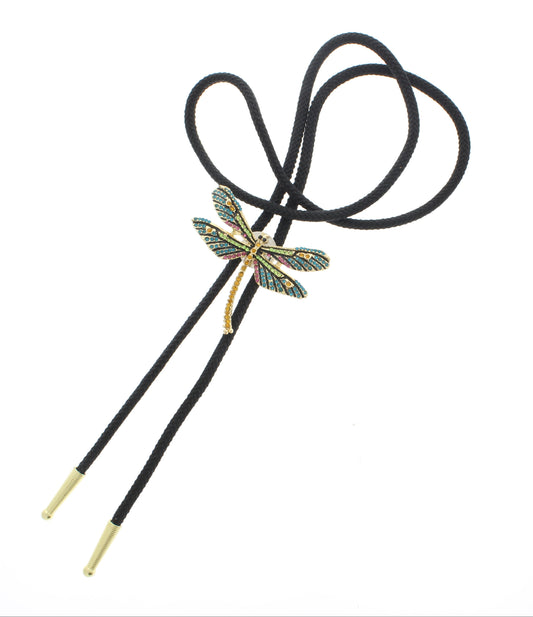 This bolo features a stunning dragonfly centerpiece adorned with colorful crystals in shades of blue, green, and pink, all accented with golden details. The black braided cord provides a bold contrast, finished with polished gold-tone tips for a refined look.